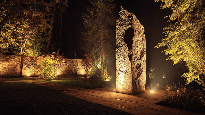 A stone monument dramatically highlighted with uplighting from the ground