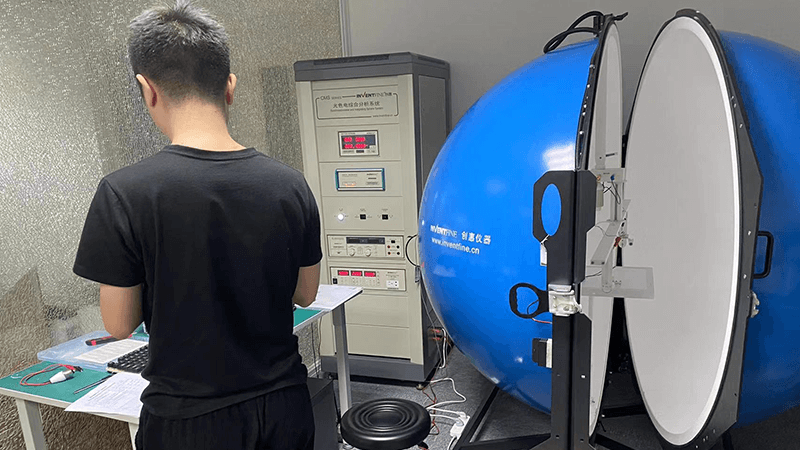 A technician placing an LED fixture inside an integrating sphere for LM-79 testing
