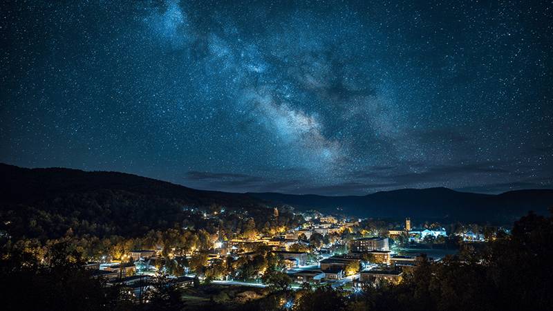 A starry night sky visible over a town with responsible, downward-facing lighting.