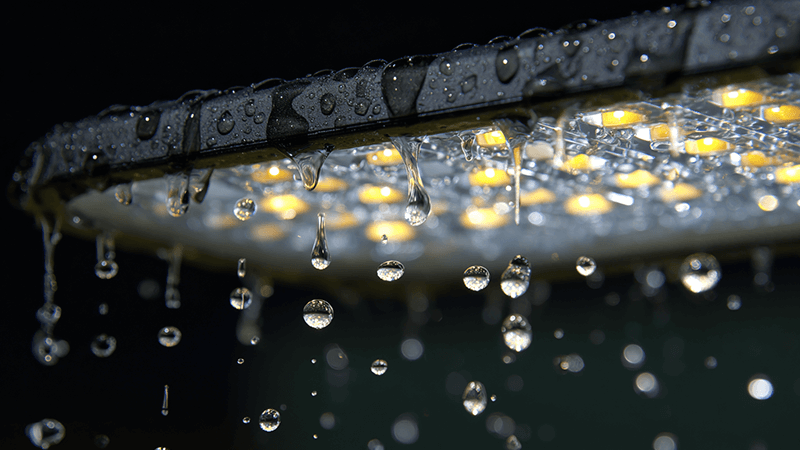Close-up of water droplets beading on the surface of an IP65 LED floodlight, showing it is properly sealed.