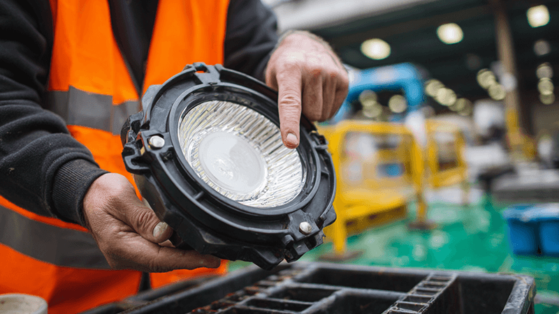 An engineer pointing to the quality silicone gasket on a disassembled IP65 LED floodlight housing.