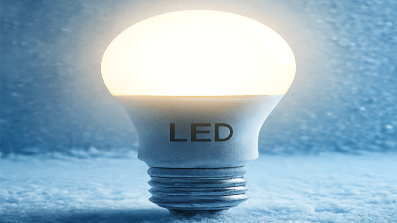 An LED light bulb glowing brightly in a frosty setting
