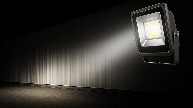 An LED floodlight casting a wide beam of light on a building exterior
