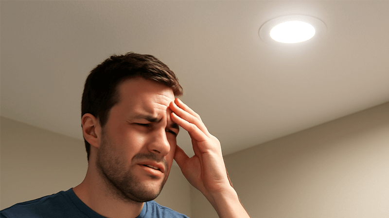 A person looking uncomfortably at a poorly chosen, glaring LED downlight.