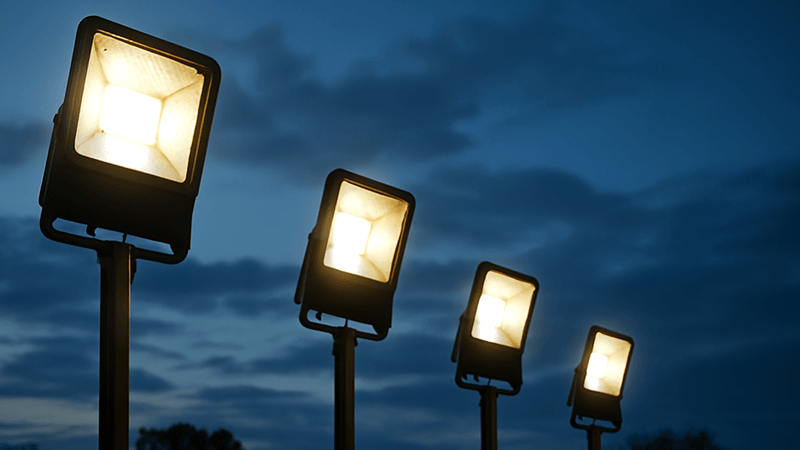 Long-lasting LED Floodlight Lifespan A row of high-quality LED floodlights illuminating an outdoor area at dusk