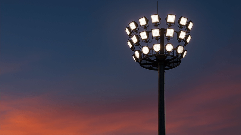 High-mast LED floodlights on a tall pole against a dusk sky