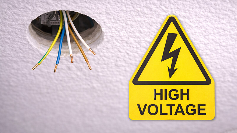 A warning sign for high voltage near a ceiling cutout
